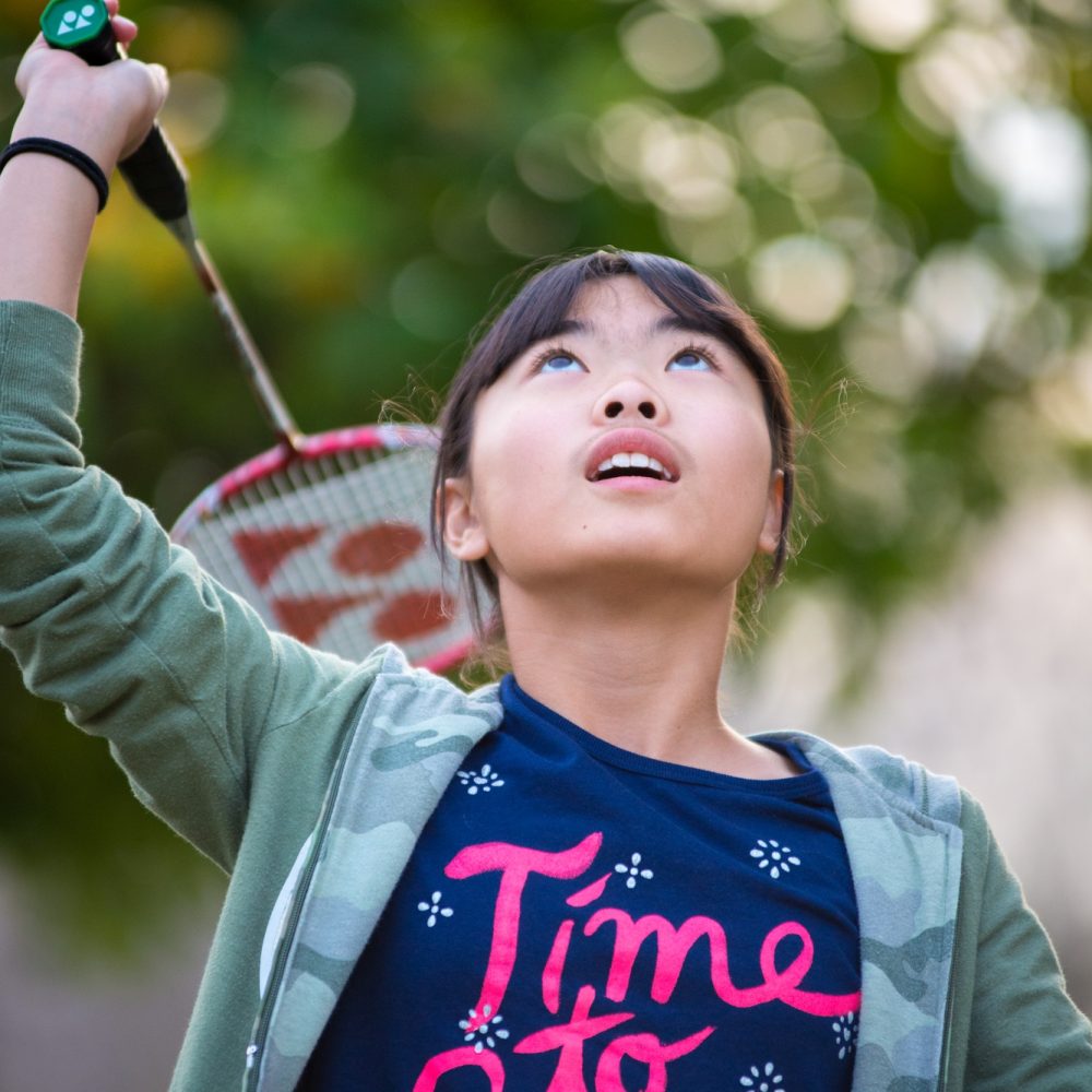 Young asain girl playing badminton in yard